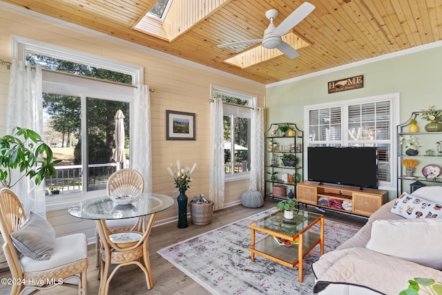 living room with wood walls, a skylight, ceiling fan, wood-type flooring, and wood ceiling