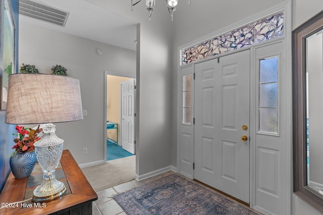 entryway featuring light carpet and a chandelier