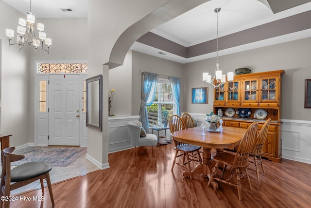 dining room featuring hardwood / wood-style floors, a tray ceiling, crown molding, and a notable chandelier