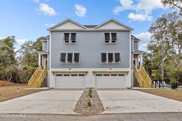 coastal home featuring a garage, stairway, and concrete driveway