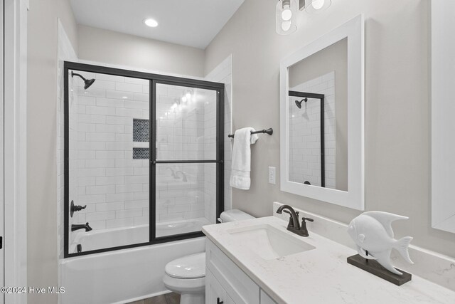 full bathroom with vanity, bath / shower combo with glass door, and toilet