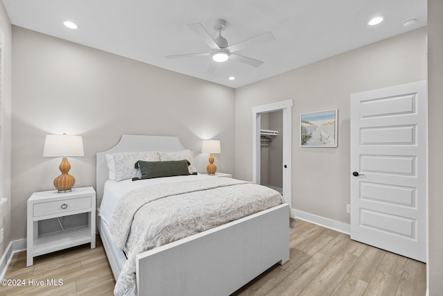 bedroom featuring ceiling fan, light wood-type flooring, a walk in closet, and a closet