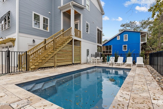 rear view of property featuring a fenced in pool and a patio