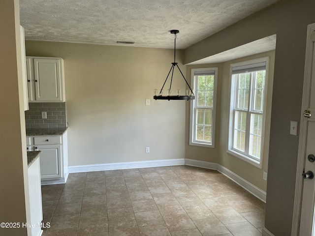 unfurnished dining area featuring light tile patterned flooring and a textured ceiling