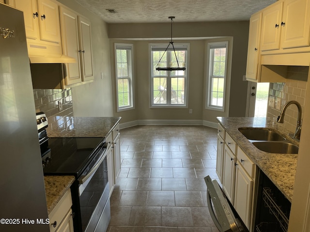 kitchen with pendant lighting, backsplash, sink, light stone countertops, and stainless steel appliances