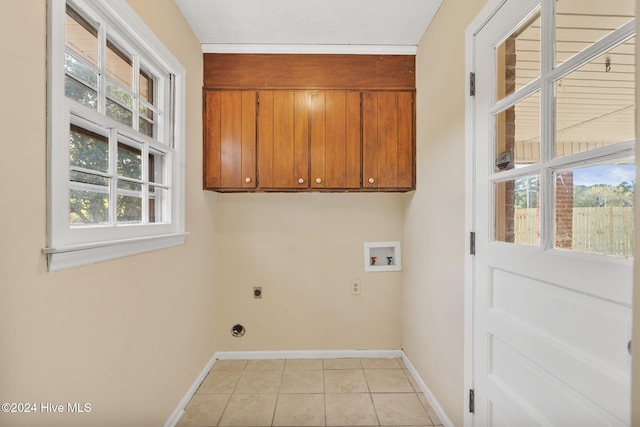 laundry room featuring hookup for an electric dryer, plenty of natural light, cabinets, and light tile patterned floors