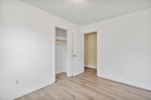 unfurnished bedroom with light wood-type flooring and a textured ceiling