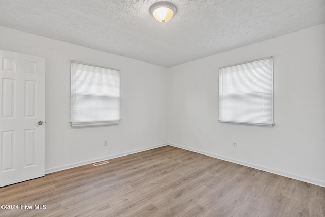 unfurnished room with light hardwood / wood-style floors and a textured ceiling