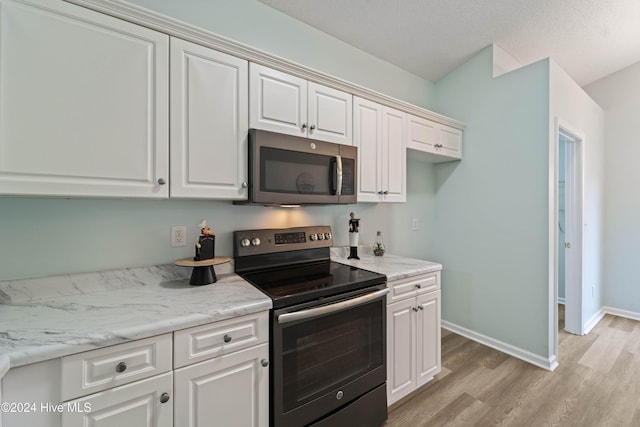 kitchen with light wood-type flooring, stainless steel appliances, white cabinetry, and light stone counters