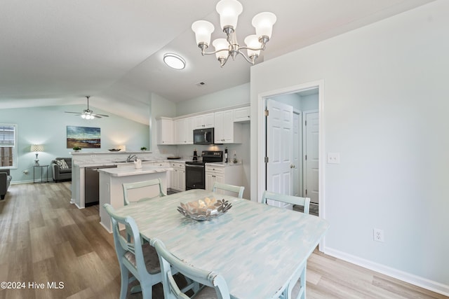 dining room with sink, ceiling fan with notable chandelier, light hardwood / wood-style floors, and vaulted ceiling