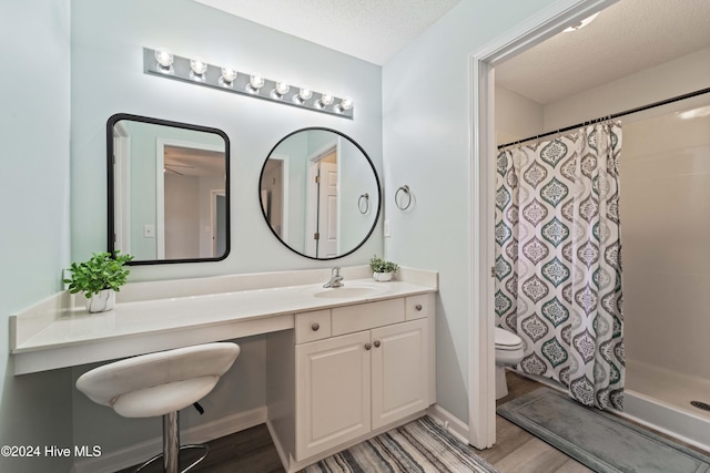 bathroom featuring a shower with curtain, a textured ceiling, toilet, vanity, and hardwood / wood-style flooring