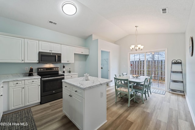 kitchen featuring appliances with stainless steel finishes, a kitchen island, white cabinetry, hanging light fixtures, and lofted ceiling