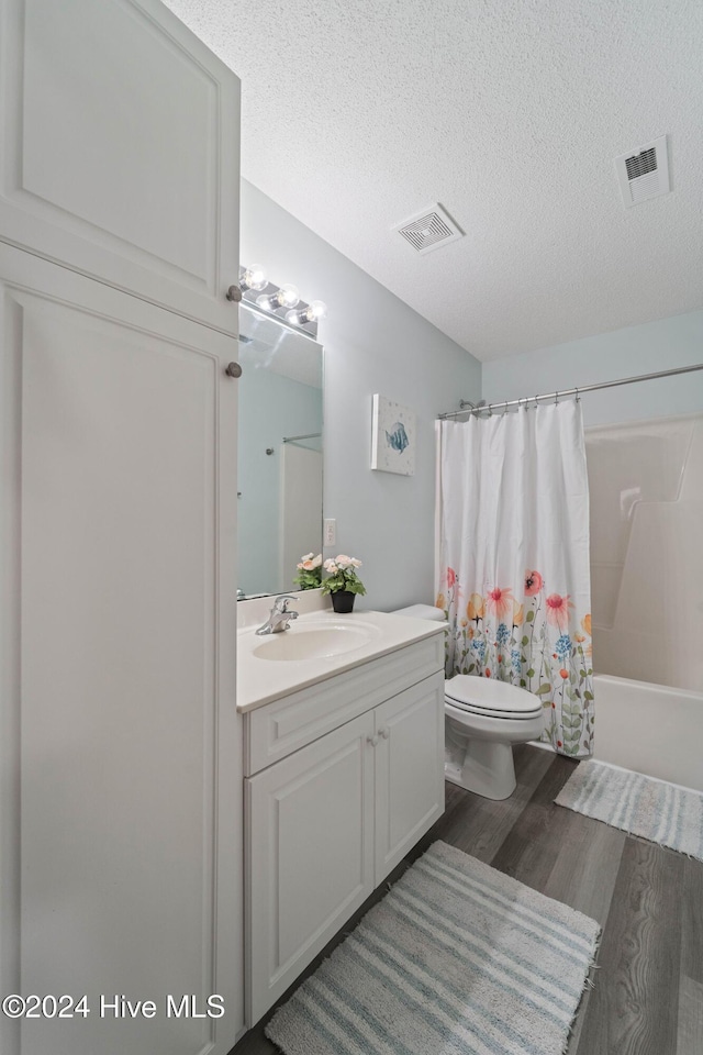 full bathroom featuring shower / tub combo with curtain, vanity, a textured ceiling, and hardwood / wood-style flooring