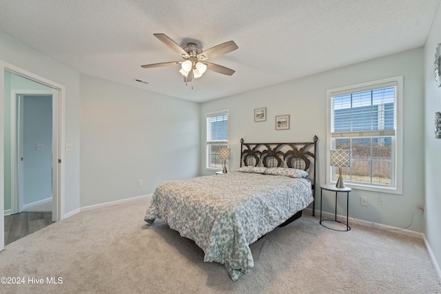 carpeted bedroom featuring ceiling fan and a textured ceiling