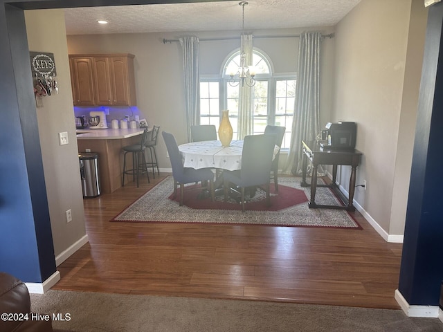 dining area featuring an inviting chandelier, a textured ceiling, and dark hardwood / wood-style floors