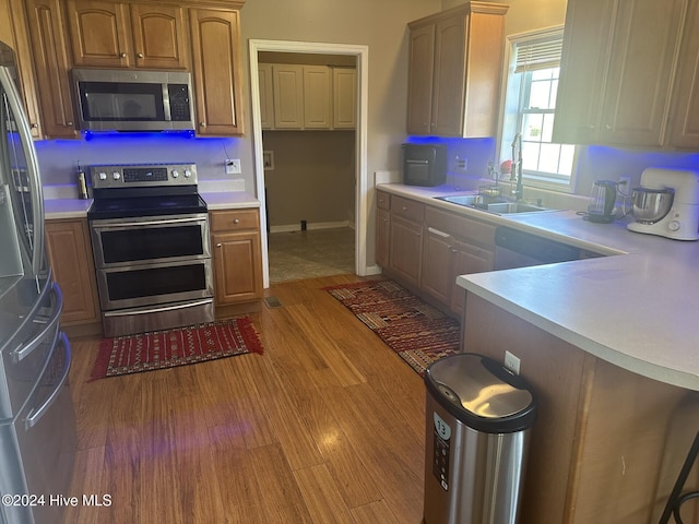 kitchen featuring appliances with stainless steel finishes, sink, and light hardwood / wood-style flooring