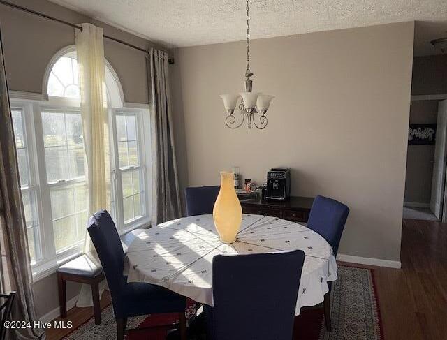 dining room with dark hardwood / wood-style flooring, a textured ceiling, and a notable chandelier