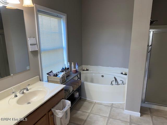 bathroom with tile patterned flooring, vanity, and plus walk in shower