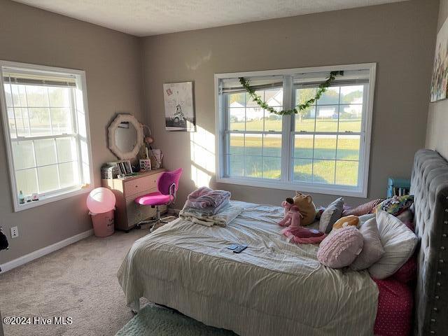 bedroom with multiple windows, a textured ceiling, and carpet