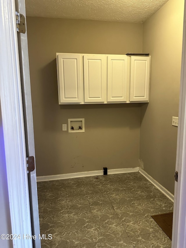 washroom with cabinets, hookup for a washing machine, and a textured ceiling