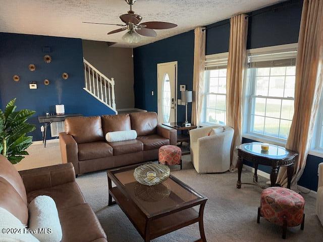 carpeted living room featuring a textured ceiling and ceiling fan