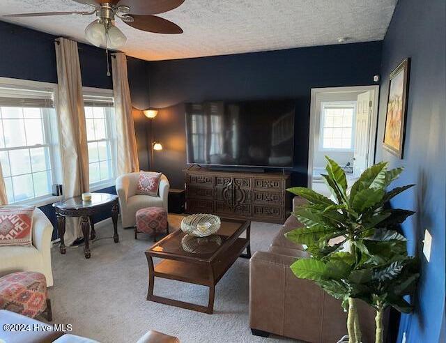 living room featuring a textured ceiling, light colored carpet, and ceiling fan