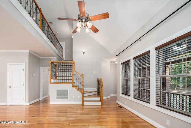 unfurnished living room with ceiling fan, light hardwood / wood-style flooring, high vaulted ceiling, and ornamental molding