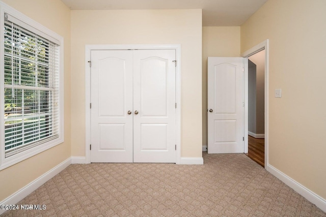 unfurnished bedroom with light colored carpet and a closet