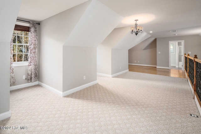 bonus room with light colored carpet, a notable chandelier, and lofted ceiling