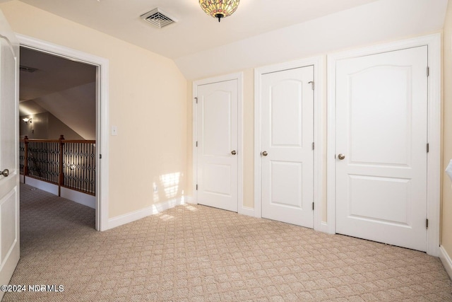 unfurnished bedroom featuring light colored carpet and lofted ceiling