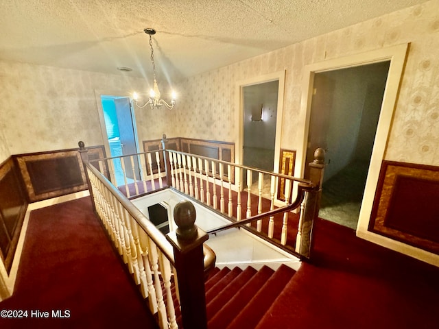 stairway featuring a chandelier, a textured ceiling, and carpet