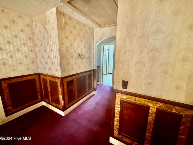 hall featuring carpet floors and a textured ceiling