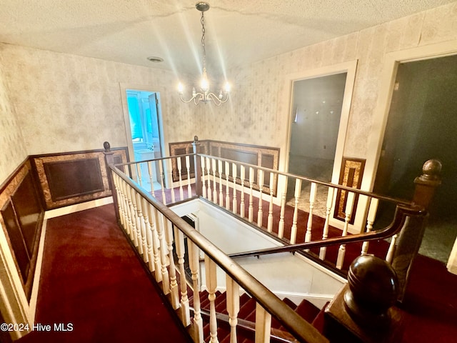 stairway featuring a textured ceiling, an inviting chandelier, and carpet