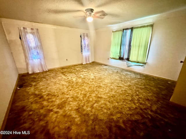 empty room with a textured ceiling, carpet floors, and ceiling fan