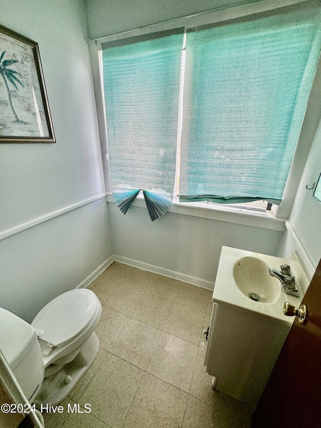 bathroom with plenty of natural light, vanity, tile patterned floors, and toilet