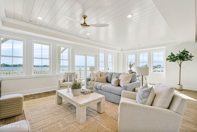 sunroom / solarium with a healthy amount of sunlight, a raised ceiling, and a water view