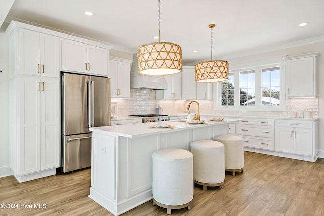 kitchen featuring a center island with sink, stainless steel appliances, light wood-type flooring, pendant lighting, and white cabinets