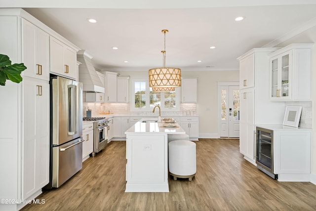 kitchen featuring stainless steel appliances, wine cooler, white cabinetry, decorative light fixtures, and custom exhaust hood