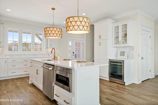 kitchen featuring light hardwood / wood-style floors, sink, backsplash, an island with sink, and white cabinets