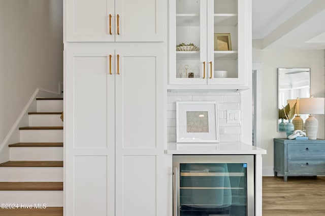 bar featuring wine cooler, wood-type flooring, and white cabinets