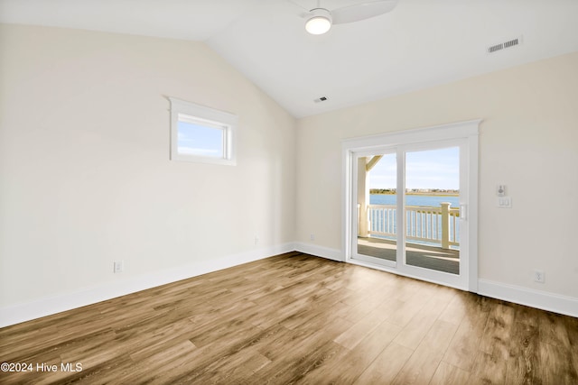 empty room featuring hardwood / wood-style floors, ceiling fan, a water view, and lofted ceiling