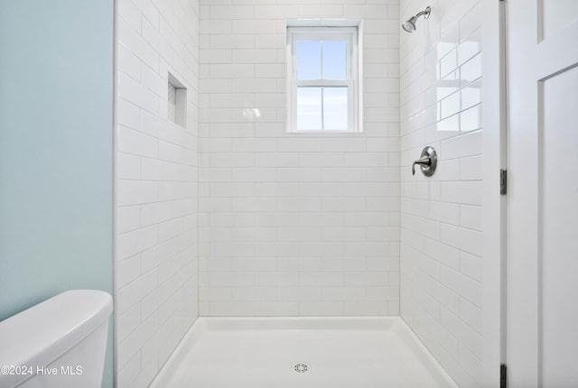 bathroom with toilet and a tile shower