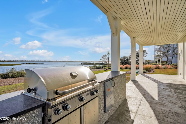 view of patio / terrace with exterior kitchen, grilling area, and a water view