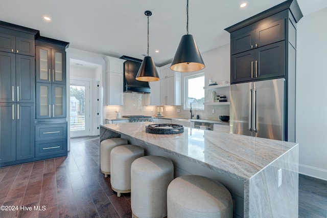 kitchen with premium range hood, pendant lighting, appliances with stainless steel finishes, and a center island