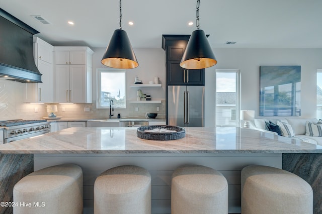 kitchen featuring white cabinetry, high quality appliances, decorative light fixtures, and light stone counters