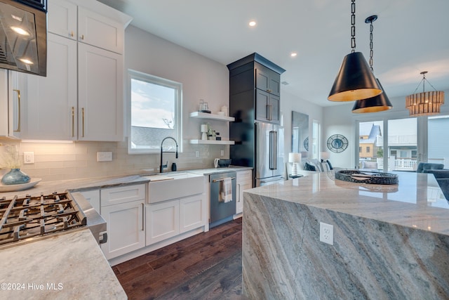 kitchen with white cabinets, appliances with stainless steel finishes, hanging light fixtures, and dark hardwood / wood-style floors