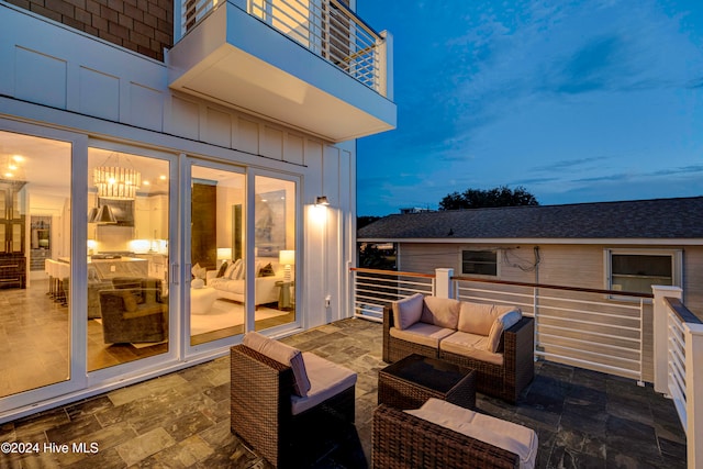 patio terrace at dusk featuring a balcony and an outdoor hangout area