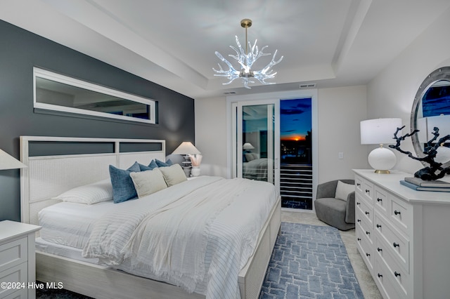 bedroom with dark colored carpet, a notable chandelier, and a tray ceiling