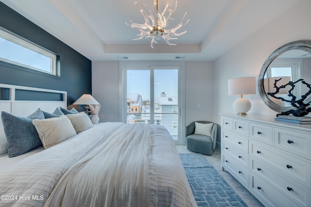 carpeted bedroom with a chandelier and a raised ceiling