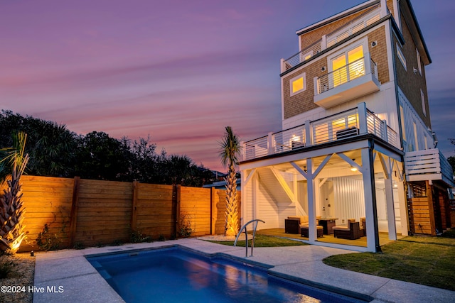 pool at dusk featuring a patio and an outdoor living space